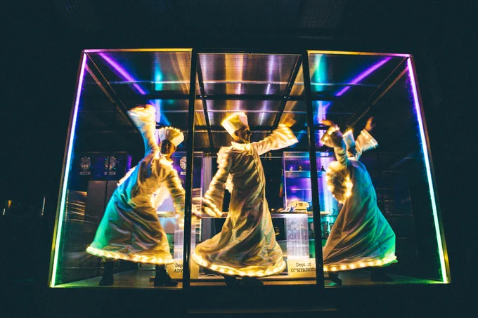 Three people in a brightly lit box posing 