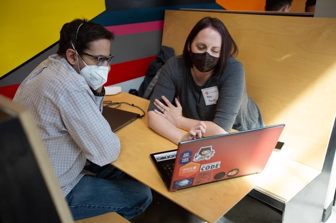 Two people sitting in a booth looking at the same laptop