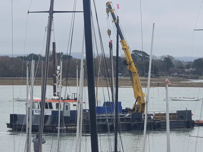 A photo of a large barge with a crane onboard on the water in the harbour