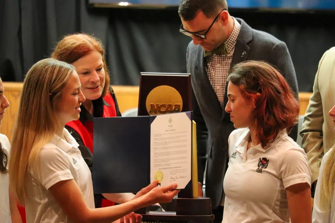 The Mayor of Raleigh presenting a proclamation to two NC State women's cross country athletes