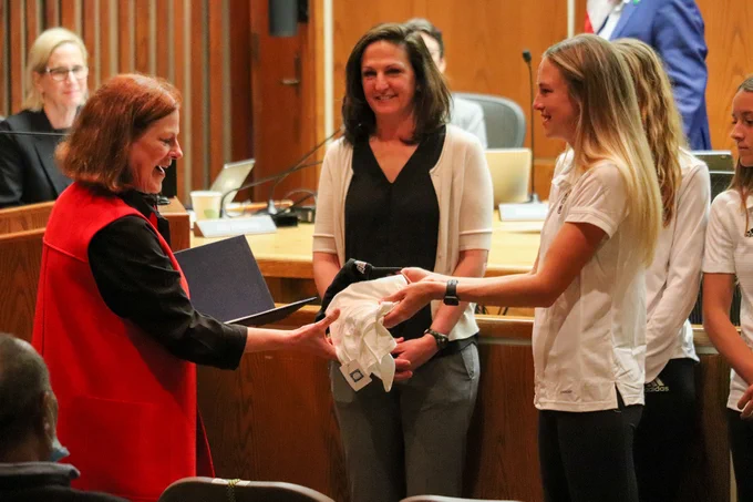 The NC State women's cross country team presenting the Raleigh Mayor with a hat and a tee shirt 