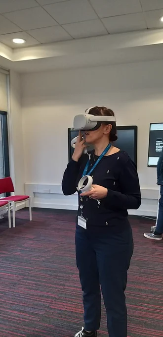 A woman wearing a virtual reality headset which has hand held controllers