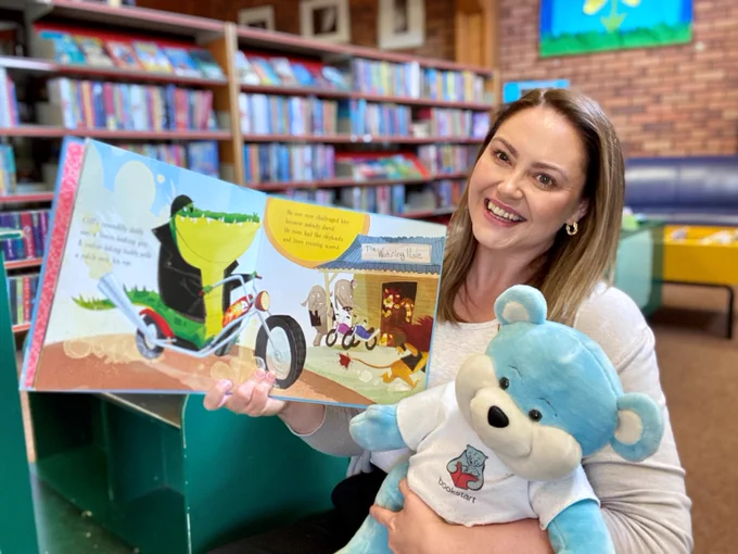 female member of staff with bookstart bear and picture book