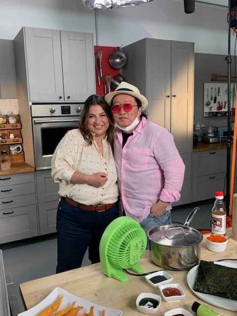 Mary and Chef Sang Kim pose on the set of Dish with Mary Season two. In front of them is a spread of sushi ingredients.