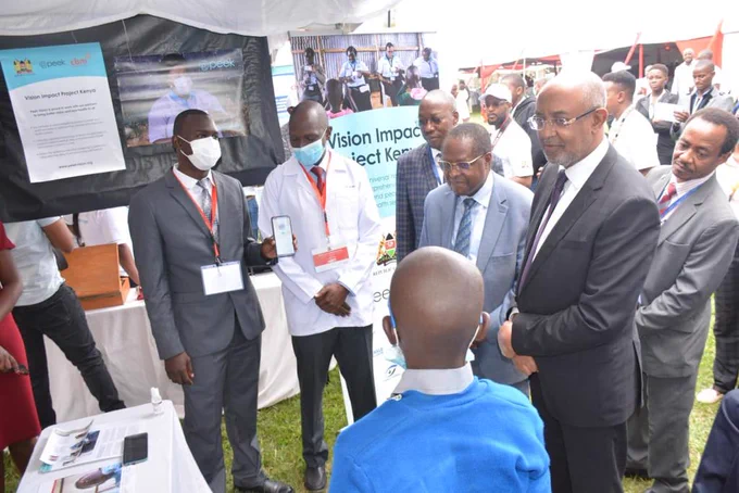 Team members Cosmas Bunywera and Dr Hillary Rono show how Peek technology is used to screen vision, in the presence of the Kenya Ministry of Health's Chief Administrative Secretary, Dr Rashid Aman, at the project launch event.