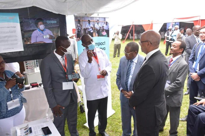 Team members Cosmas Bunywera and Dr Hillary Rono demonstrate Peek technology to the Kenya Ministry of Health's Chief Administrative Secretary, Dr Rashid Aman, at the project launch event.