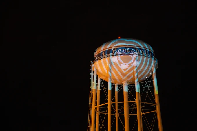 The Heartland Summit logo is illuminated onto the Bentonville water tower at night.