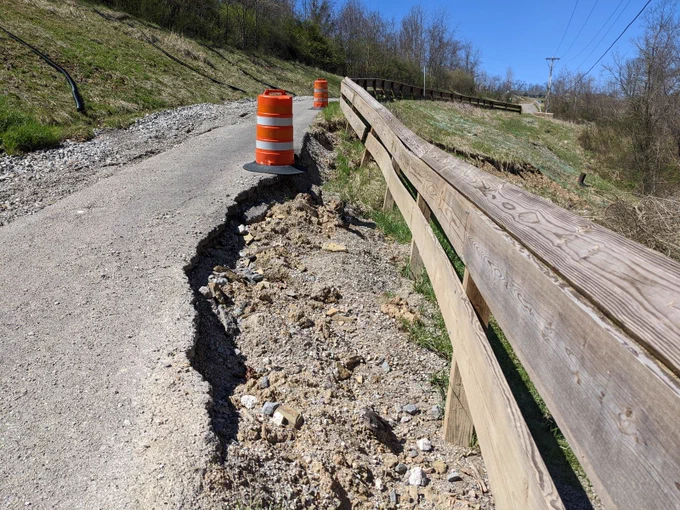 A bike path with a giant gouge missing due to erosion and collapse.