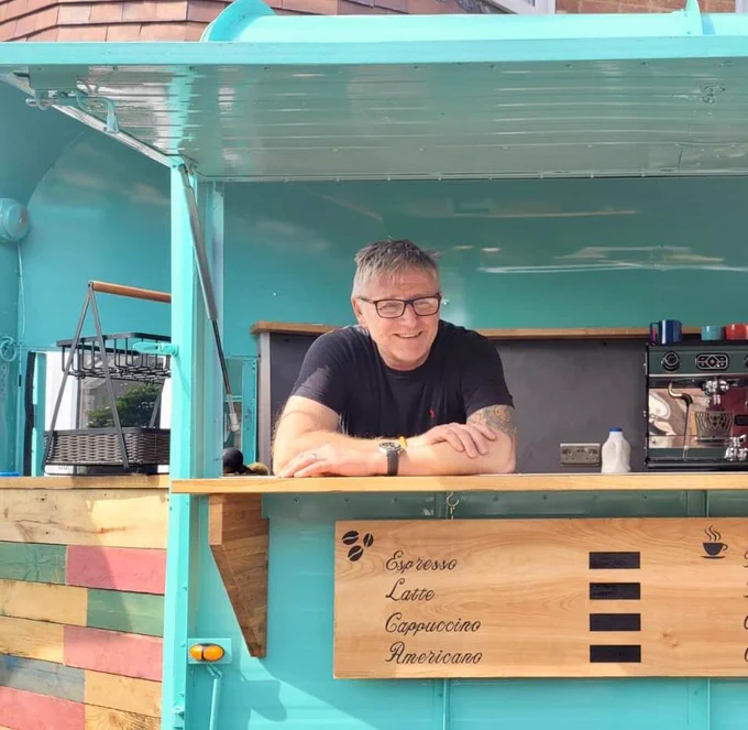 A man leans on the counter at the new coffee shop, made out of an old horsebox