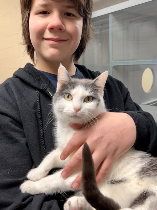 Nigel holding a white and grey cat (Beth) with yellowish-greenish eyes.