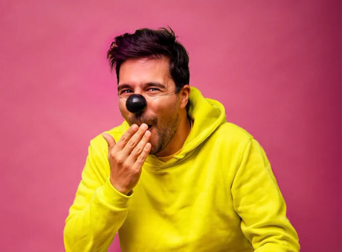 Cheeky looking man, smiling with yellow hoodie and brown button nose