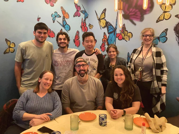 A group of people sitting at a restaurant table with butterfly themed decorations in the background.
