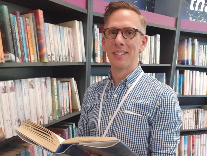 male member of staff in library with books