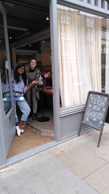 Photo of Dama and Liv in the doorway of Newspeak House, with a sign reading TECH FOR GOOD outside