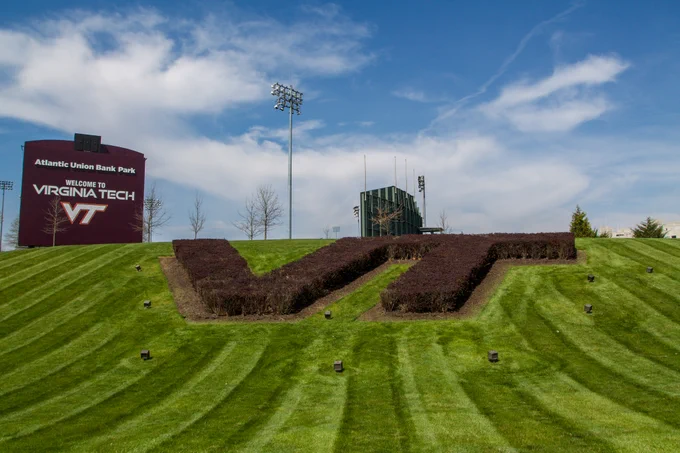 A hedge shaped like the Virginia Tech logo surrounded by green grass on a sunny day