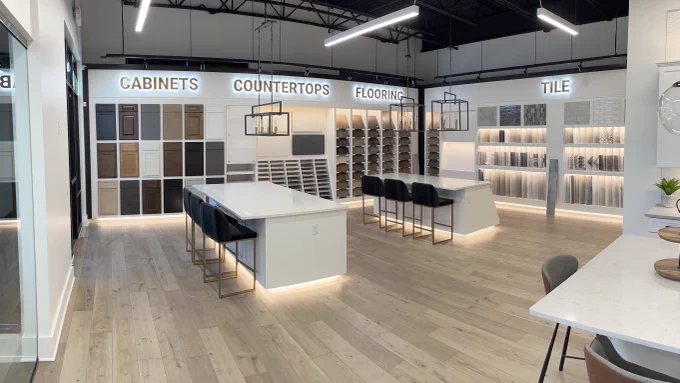 Design studio showroom with two kitchen islands and cabinet samples hanging on walls.