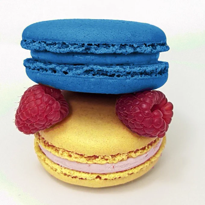 two macarons stacked with two raspberries between them