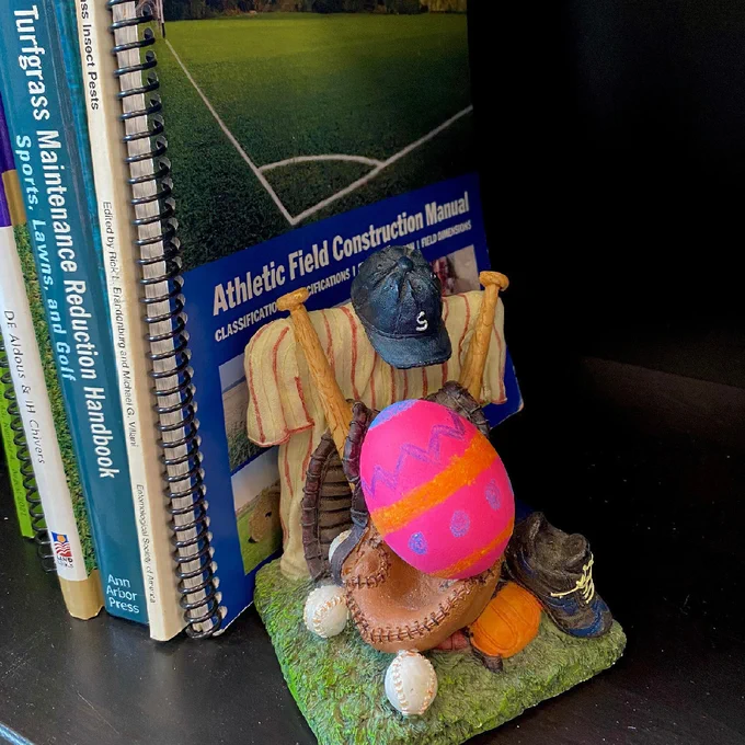 A painted Easter egg sitting on a bookshelf