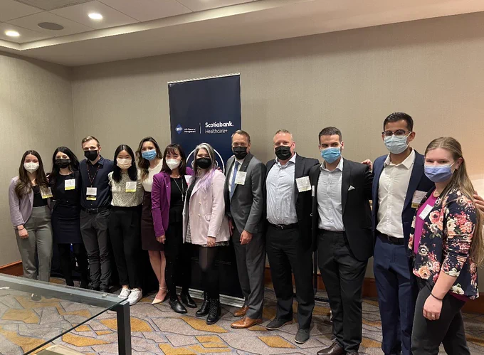 A group of 12 individuals standing in front of a poster that says “MD Financial Management” and “Scotiabank Healthcare ”.