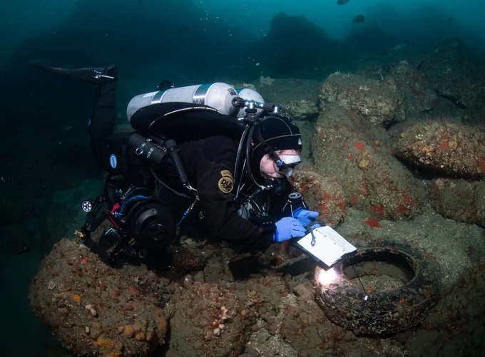 Diver surveying the seafloor for old tires.