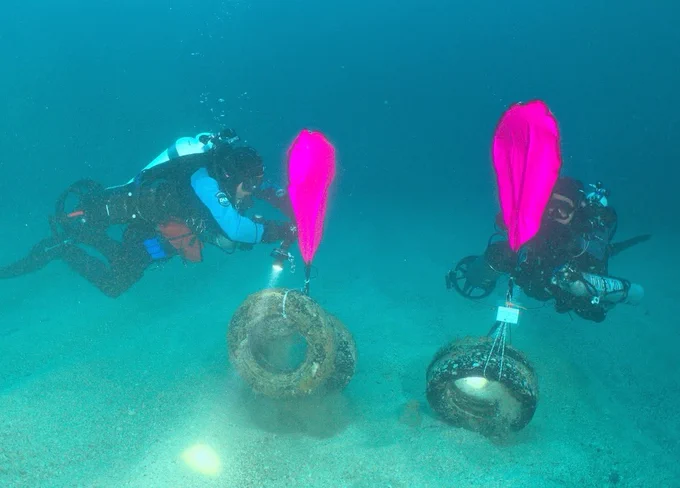 Divers removing tires with lift bags.