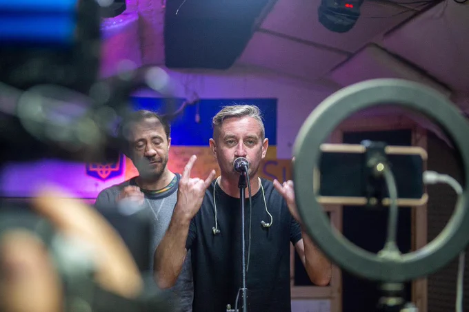 A photograph of Ukrainian writer and Kharkiv-native Serhiy Zhadan, speaking into a microphone to present his translation of “Go the Fuck to Sleep.” April 16, 2022 from a bomb shelter in Kharkiv.