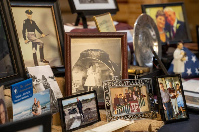 A memorial filled with framed photos of important moments throughout this life. Prominent photos include his corps portrait, an image of him at Ring Dance, and photo of a large group of people reading the word "family". 