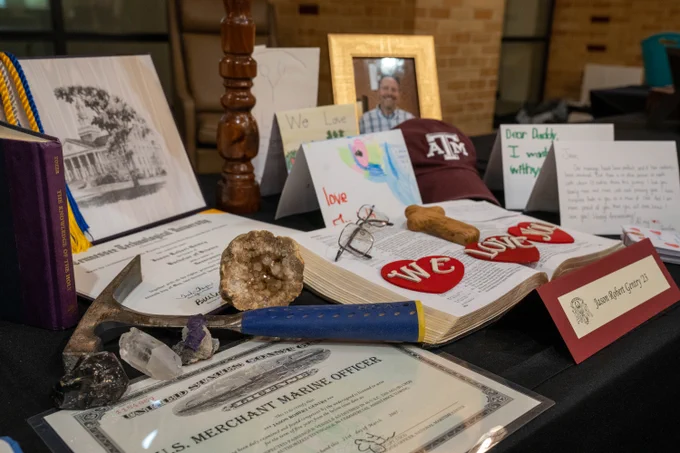 Jason Robert Gentry '23's memorial includes a certification of a U.S. Merchant Marine Officer, a large bible, cards, and graduation cords. It also includes the words "we lobe you" on red hearts laid on top of a Bible. 