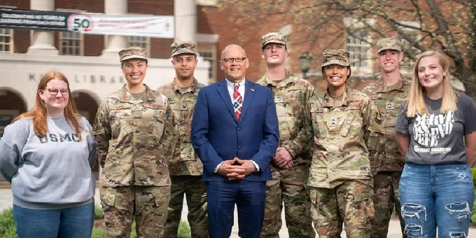 President Crawford with students in military uniforms outside of King Library. 