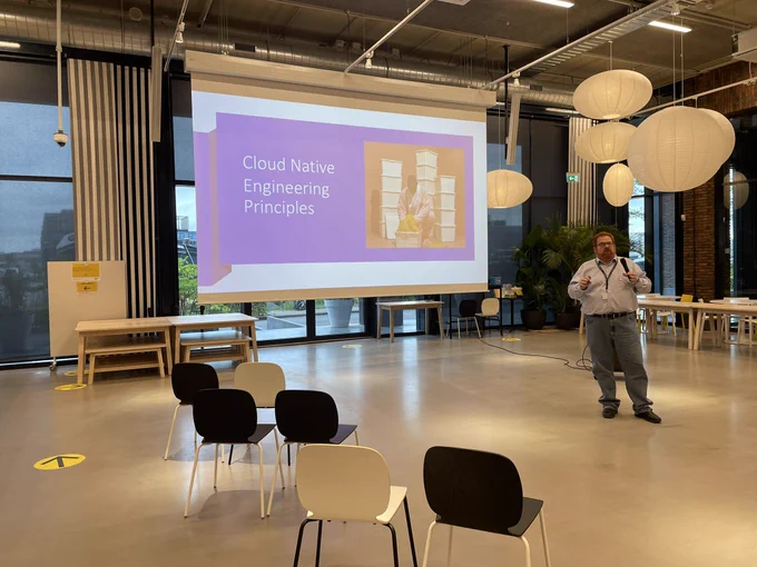 Speaker in front of slide. The slide shows a person in surrounded by lots of IKEA containers and is titled “Cloud Native Engineering Principles”
