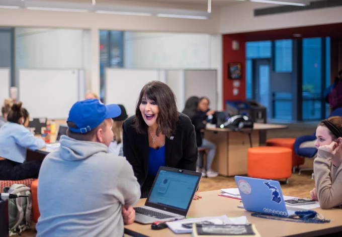 Philomena Mantella talking happily with a student in the library.