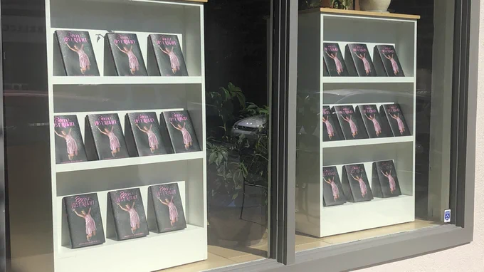 Two bookshelves inside a bookstore window filled with copies of Born Just Right.