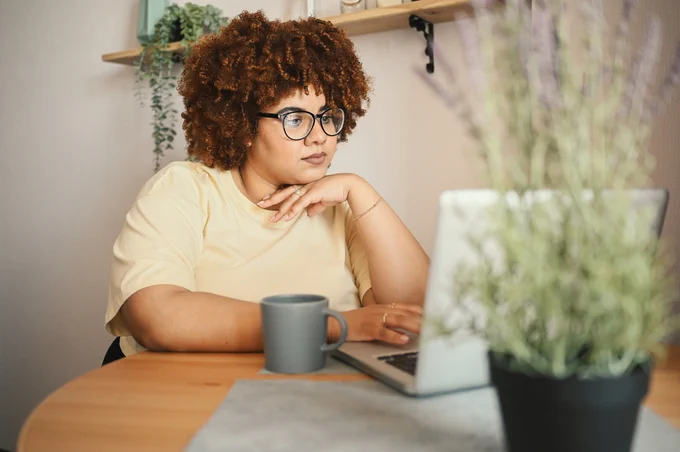 A black woman with curly hair using her laptop