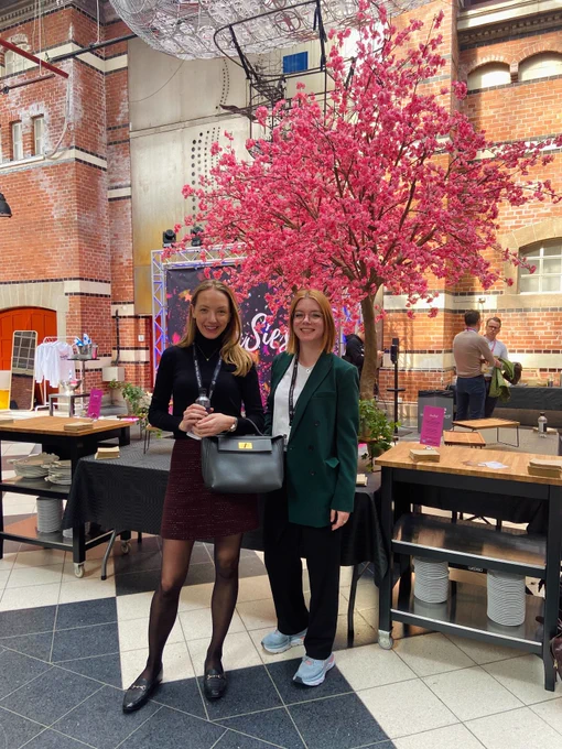 Two businesswomen posing in front of a blooming tree at the event SaaSiest located in Malmö, Sweden.