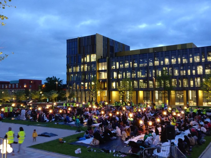 Community Iftar with people sat on the grass outside the University of Birmingham library