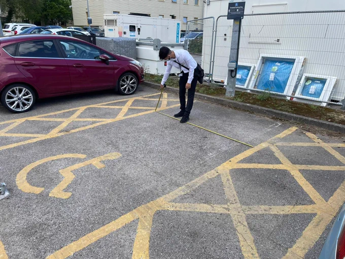 AccessAble surveyor measuring the dimensions of an accessible car parking space at Milton Keynes Hospital.