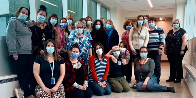 Masked Administrative Professionals gathered in hallway.