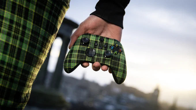 Graphic depicts a green and black tartan controller being held in front of a light background. 
