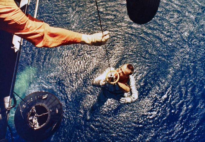 A helicopter from the U.S.S. Lake Champlain hoists Alan B. Shepard from his spacecraft following splashdown.