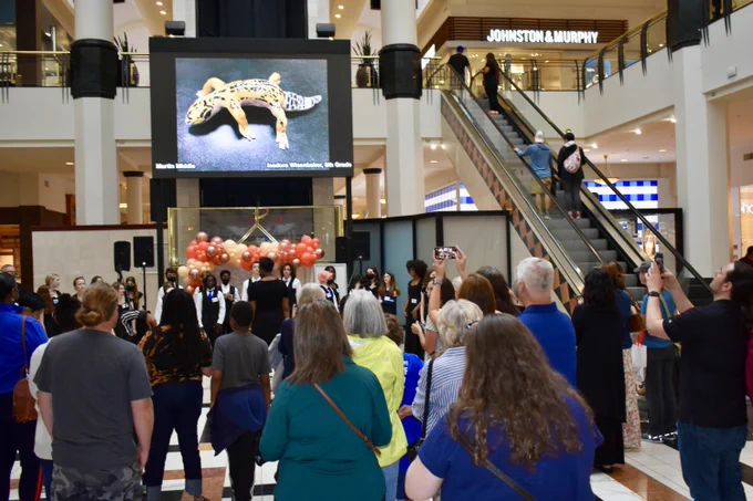 Parents and friends enjoying the performance from the Ligon Middle School Chorus with the Gifts of Gold artwork on the screen above.
