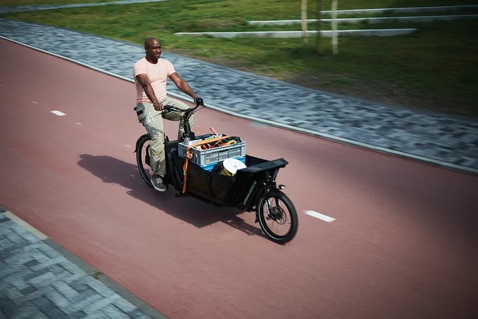 Man riding an Urban Arrow cargo bike carrying tools.