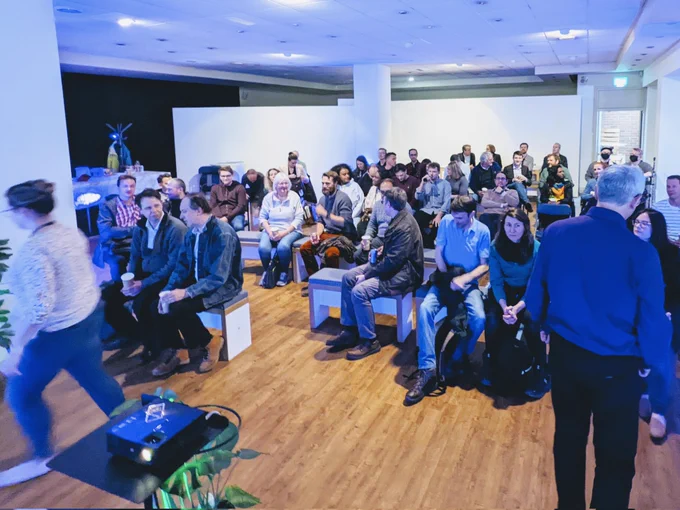 Photograph of a group of people sat down inside the MAKETANK space, getting ready to watch presentations
