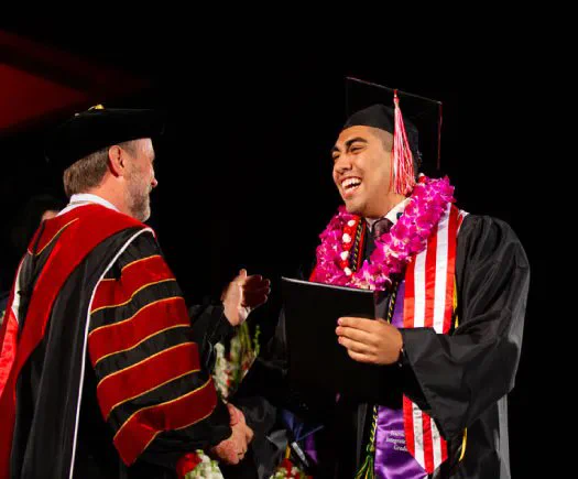 President Corey giving out a diploma to a graduating student.