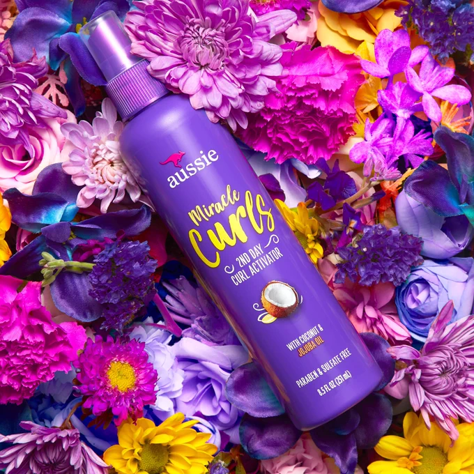 Aussie Miracle Curls 2nd Day Curl Activator laying in a bed of flowers.