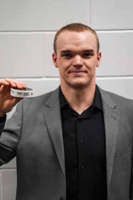 Karson Kuhlman holding up his milestone puck after his 100th nhl game