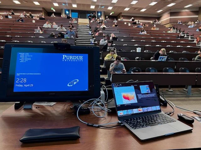 A monitor and room of students before the start of class