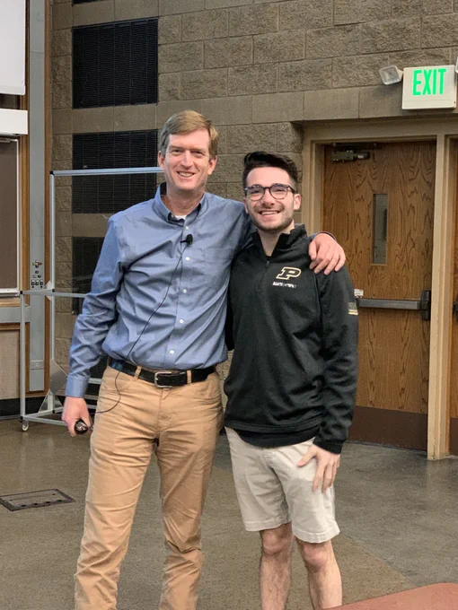 Image of professor and student smiling at the front of classroom before last class begins.