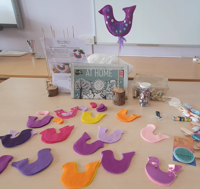 A colourful felt bird on a stick and material for making birds