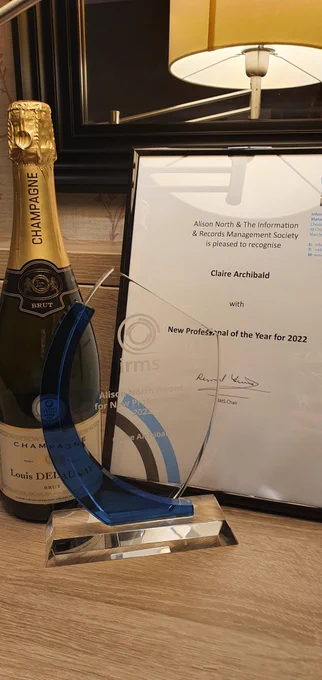 An award trophy, a bottle of champagne and a certicate 