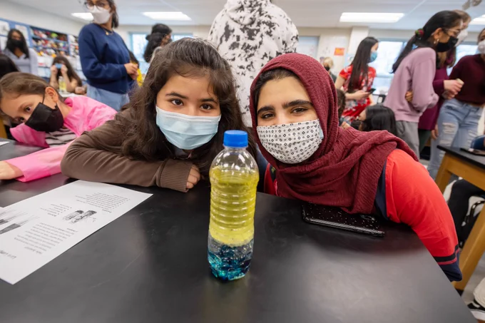 A TJHSST student and a fifth-grader from Weyanoke ES watch as they successfully complete a chemistry experiment that led to their water bottle glowing like a lava lamp.